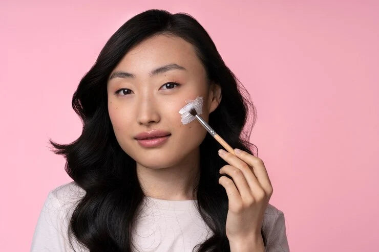 women with pink background doing makeup